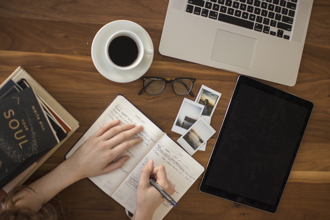 A person working in a coffee shop and writing in a journal.